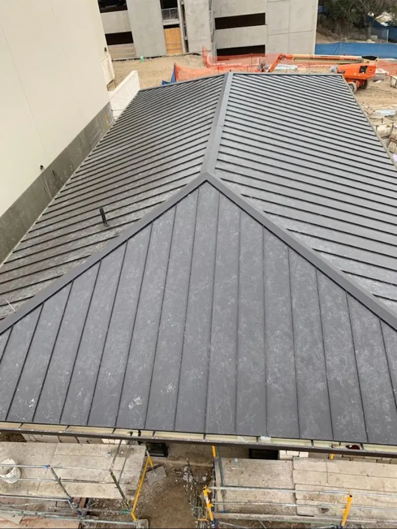 Commercial metal roof construction with crane equipment in Wixom